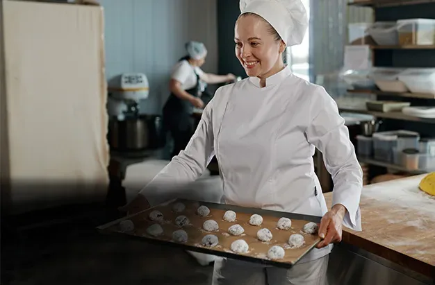 Baker preparing cookies in a commercial kitchen using professional cookie machines and confectionery depositors from Erika Baking Equipment.