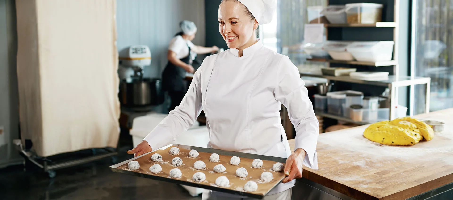 Baker carrying tray with cookies shaped from dough and prepared for baking