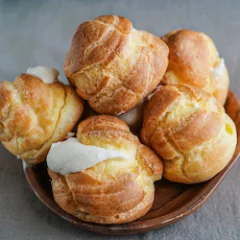 Choux Cream Puff Custard Whipped Cream Filling on a wooden plate and being put on the pillow