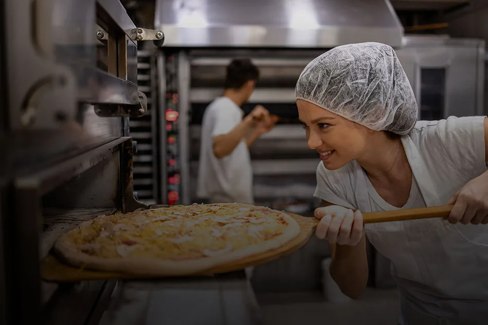 Pizzeria preparing dough using commercial mixers, dough rounders, and electric pizza ovens provided by Erika Baking Equipment.