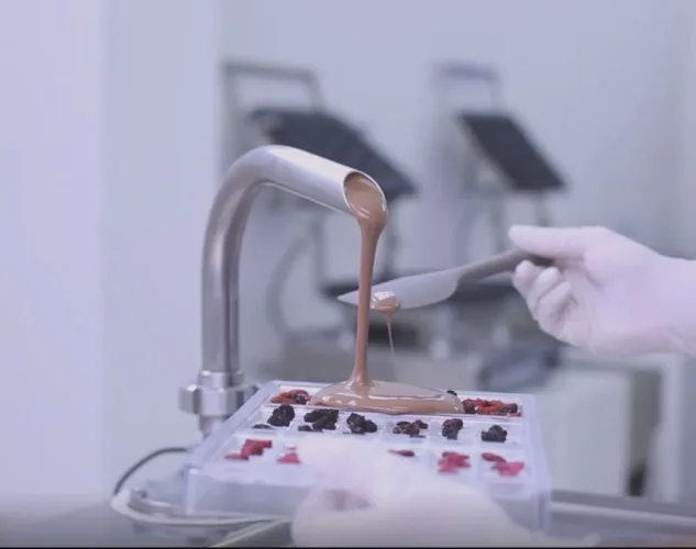 Bilait Adam K6 chocolate tempering machine dispensing tempered chocolate into bonbon mold