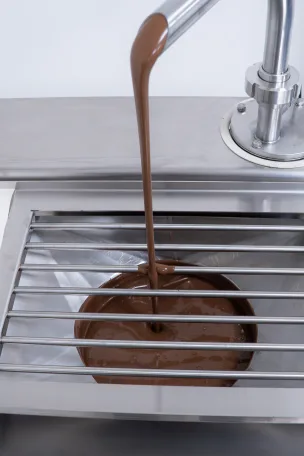 Bilait Adam K6 chocolate tempering machine dispensing tempered chocolate from outlet spout