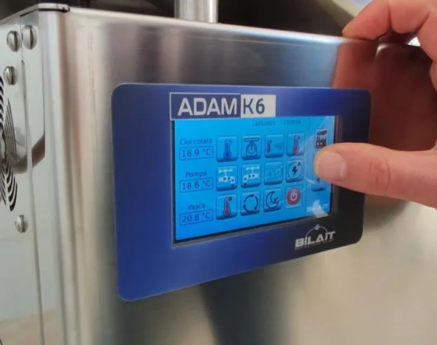 operator using touchscreen controls on the Bilait Adam K6 chocolate tempering machine