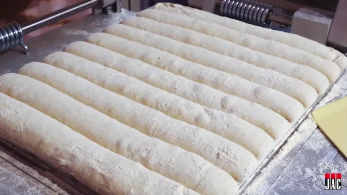 Close-up gallery image of long dough pieces formed in the JAC Tradiform moulding grid during long-product bread production.