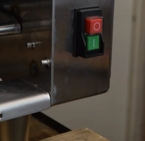 Red stop and green start buttons in a black housing on brushed stainless steel. These are the start and stop controls on the Dough Tech CM275 countertop bread and bolillo moulder.